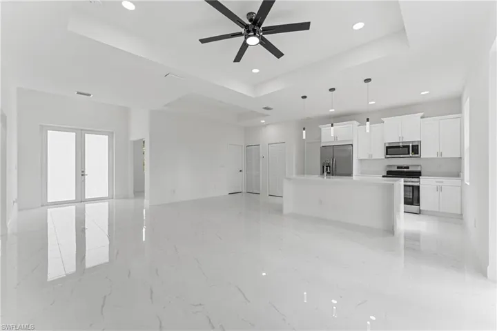 Unfurnished living room featuring french doors, recessed lighting, a raised ceiling, visible vents, and ceiling fan