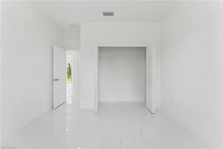 Unfurnished bedroom with marble finish floor, visible vents, and baseboards