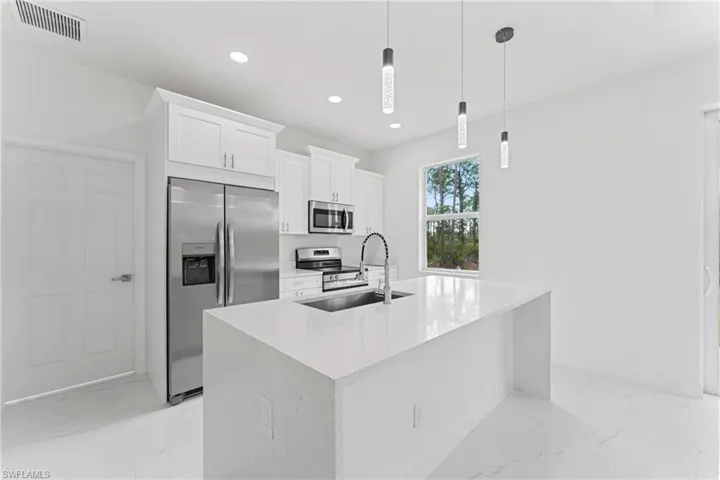 Kitchen with marble finish floor, visible vents, appliances with stainless steel finishes, white cabinets, and a sink