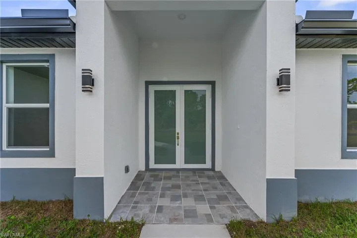 Property entrance with a standing seam roof, metal roof, french doors, and stucco siding