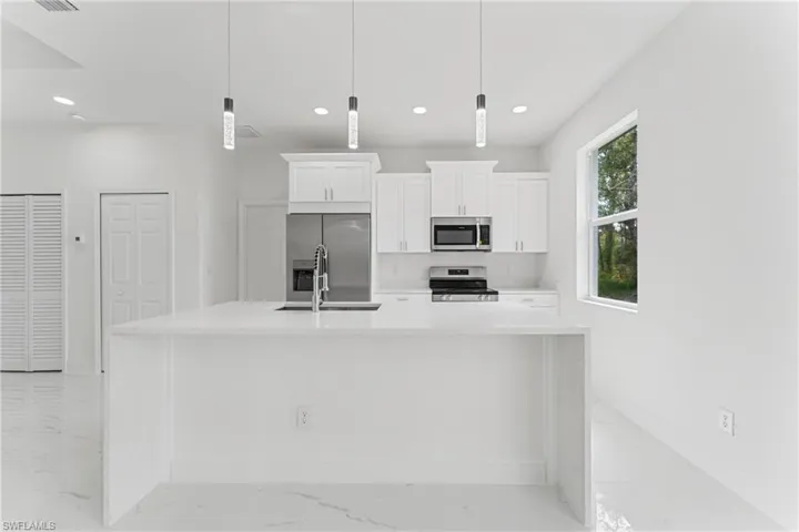 Kitchen featuring white cabinets, appliances with stainless steel finishes, marble finish floor, light countertops, and recessed lighting