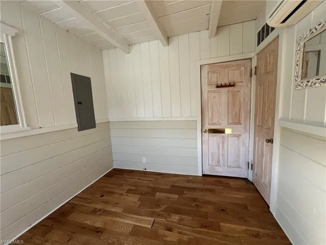 Current  view guest bedroom with dark wood-type flooring and wooden walls