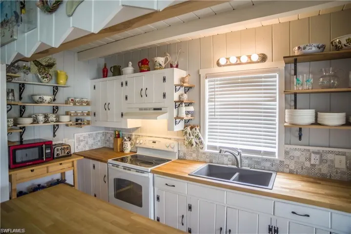 Kitchen prior to Hurricane Helene featuring butcher block countertops, electric range, and white cabinets