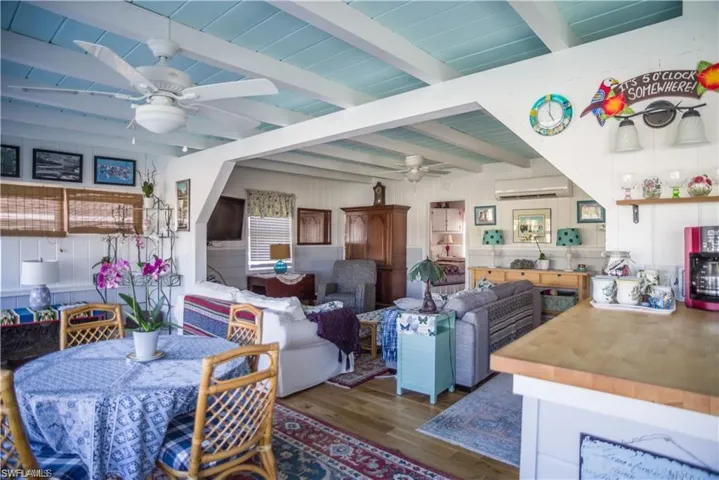 view of Dining space and living room prior to Hurricane Helene with beam ceiling, wood-type flooring, and ceiling fan