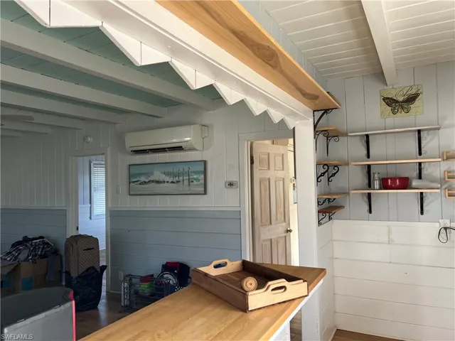 Current view from kitchen wood walls, a wall mounted AC, beamed ceiling, and dark hardwood / wood-style floors
