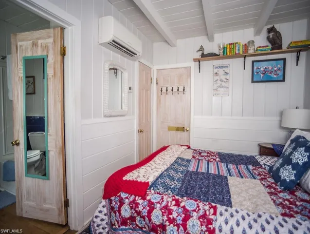 Primary Bedroom prior to Hurricane Helene featuring beam ceiling, wooden walls, and a wall mounted Mini Split AC/HEAT