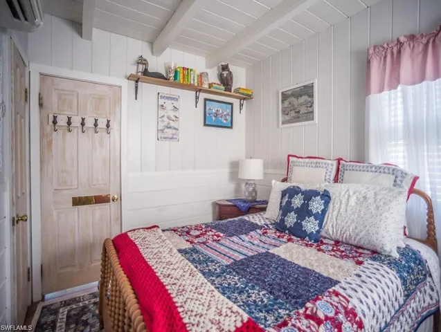 Primary Bedroom prior to Hurricane Helene featuring beam ceiling, wooden walls, and a wall mounted Mini Split AC/HEAT