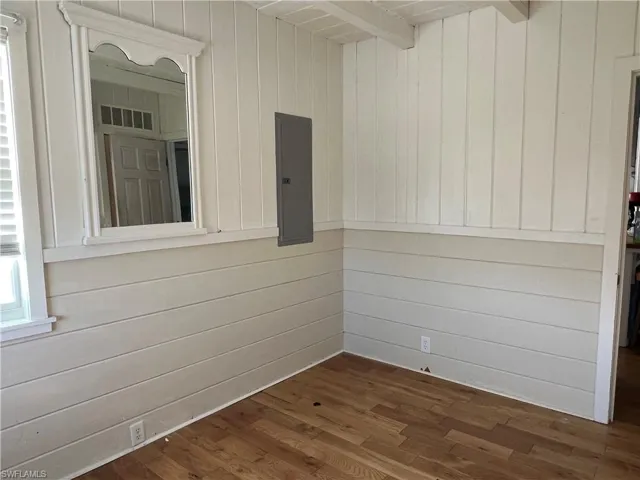 Current  view guest bedroom with dark wood-type flooring and wooden walls