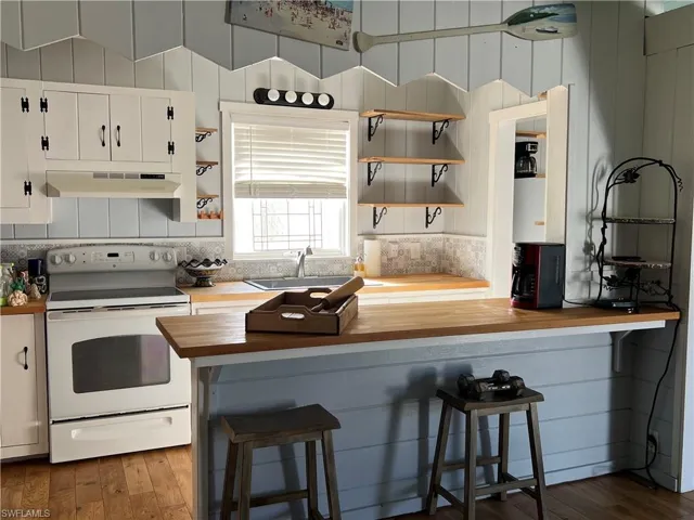 Current  Kitchen featuring white cabinets, electric range, a breakfast bar, dark hardwood / wood-style floors, and sink