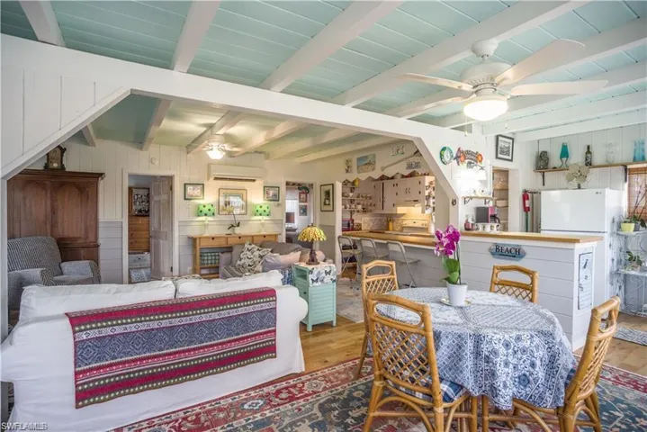 Dining area prior to Hurricane Helene featuring ceiling fan, an AC wall unit, light hardwood / wood-style flooring, and  ceiling with beams