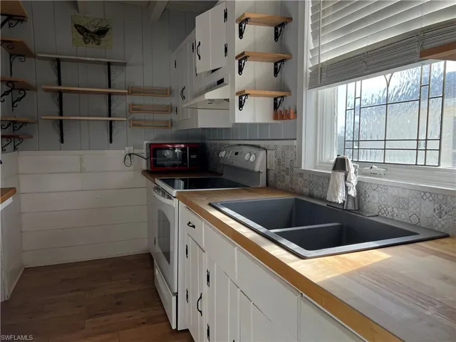 Current  Kitchen featuring dark hardwood / wood-style floors, sink, white range with electric cooktop, white cabinets, and tasteful backsplash
