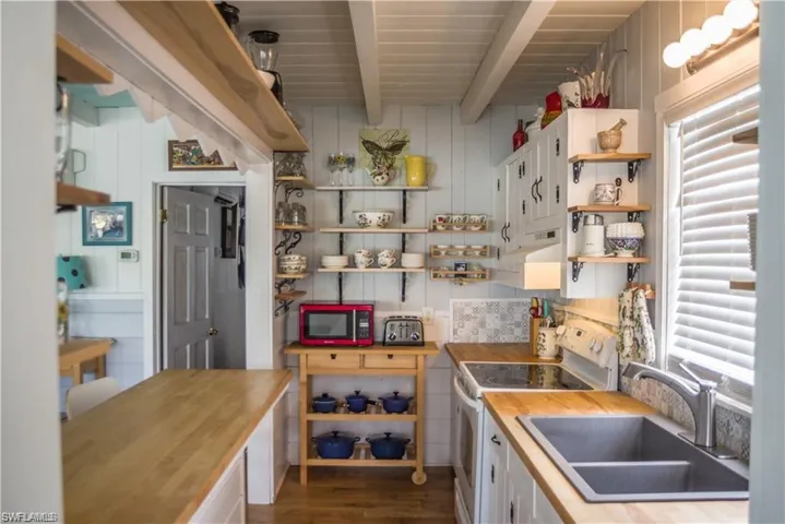 Kitchen prior to Hurricane Helene  featuring white electric range, sink, butcher block counters, and hardwood / wood-style floors