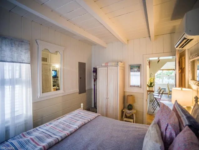 Guest Bedroom prior to Hurricane Helene featuring a and a wall mounted Mini Split AC/HEAT, newer electric panel installed after Hurricane Ian , beamed ceiling, and wooden walls