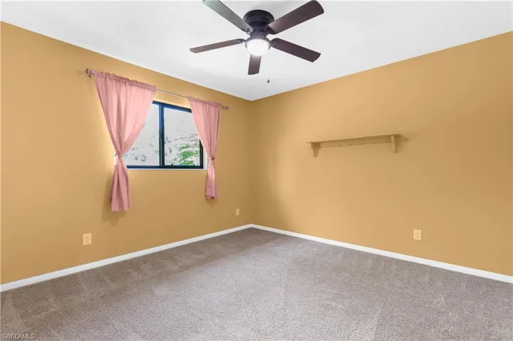 Empty room featuring carpet floors, a ceiling fan, and a textured ceiling