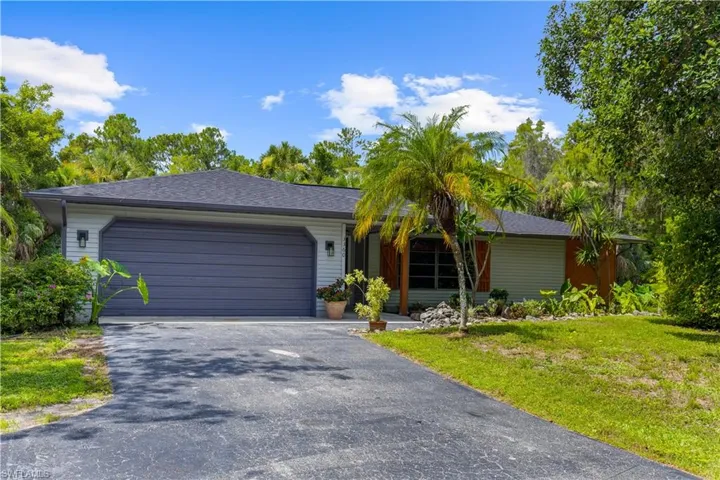 Ranch-style home featuring driveway, a garage, a front lawn, and a shingled roof
