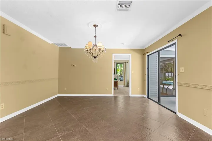 Unfurnished dining area featuring crown molding, a chandelier, and dark tile patterned floors
