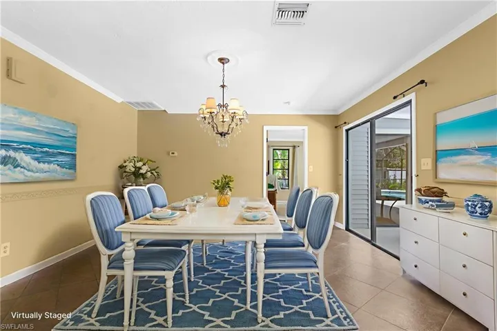 Dining room with ornamental molding, tile patterned flooring, and a chandelier