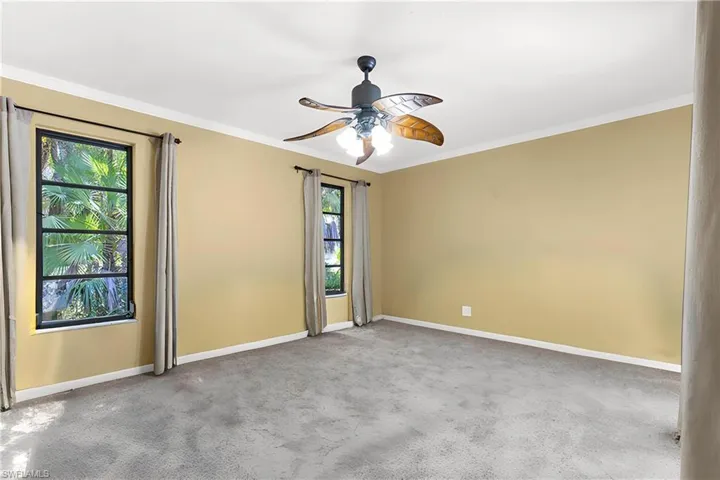 Carpeted spare room featuring ornamental molding and a ceiling fan