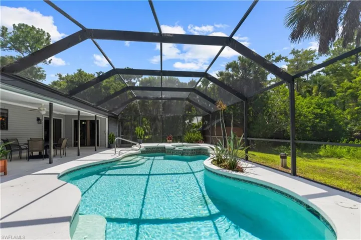 View of pool featuring a pool with connected hot tub, a patio area, ceiling fan, and a lanai