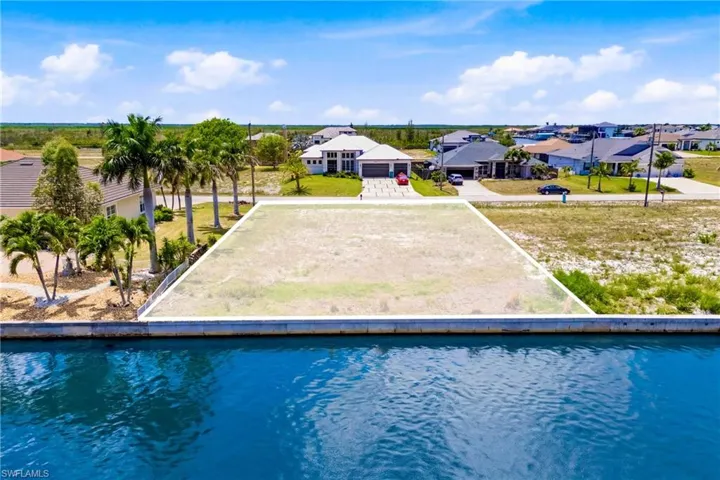 Waterfront parcel featuring a defined lot boundary, existing seawall, and surrounding residential properties