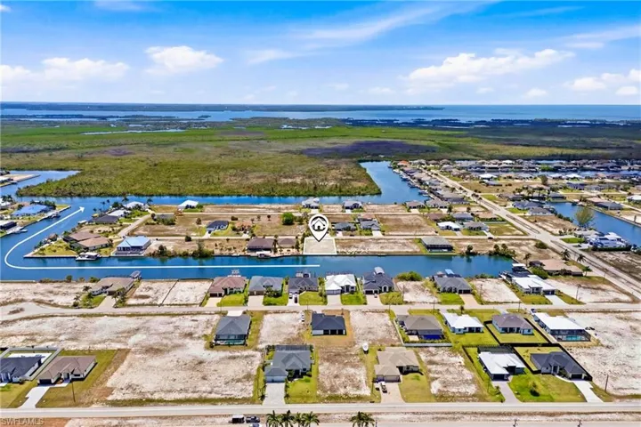 Aerial view of a developed canal-front neighborhood with scattered homes and vacant lots