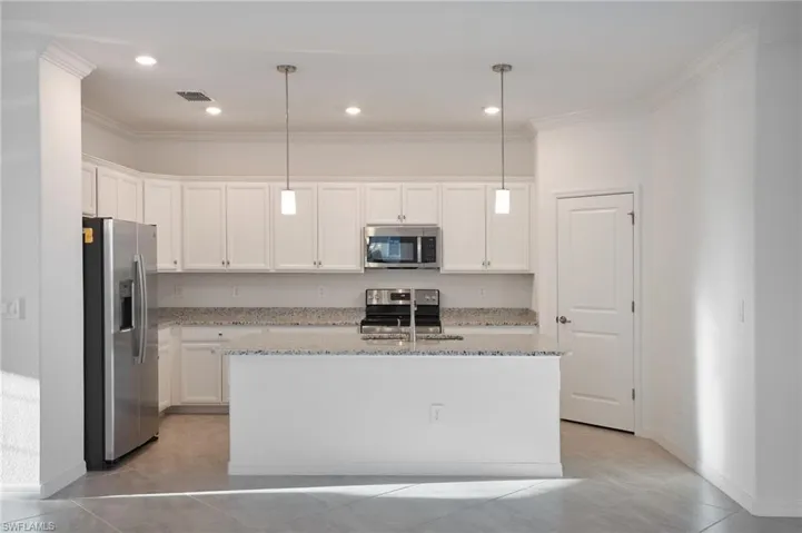 Kitchen with pendant lighting, stainless steal appliances, sink, and white cabinets