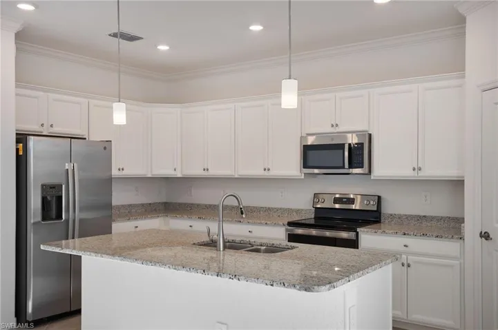 Kitchen with pendant lighting, stainless steal appliances, sink, and white cabinets
