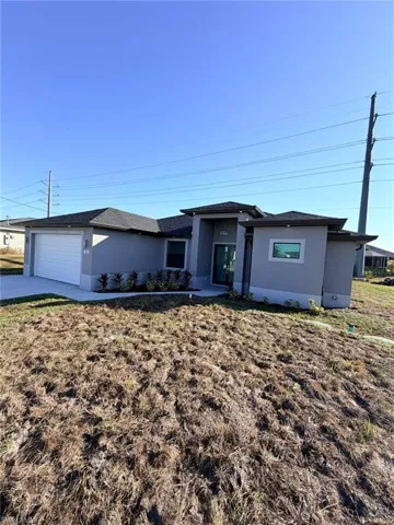 View of front of house with stucco siding, an attached garage, concrete driveway, and a front lawn