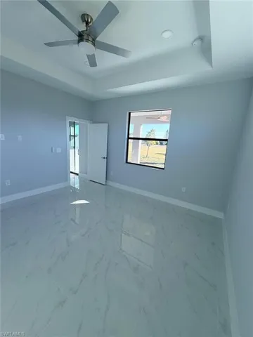 Unfurnished room featuring marble finish floors and a raised ceiling