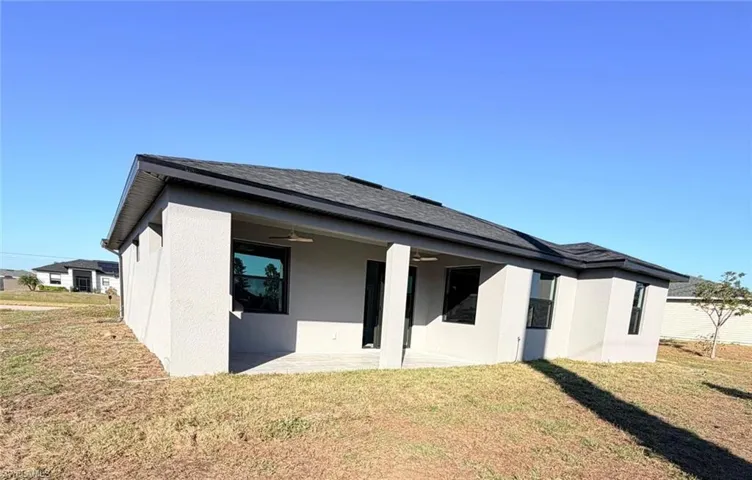 Rear view of property featuring a yard, a patio, ceiling fan, and stucco siding