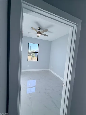 Unfurnished room with light marble finish floors and a ceiling fan