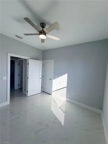 Unfurnished bedroom featuring light marble finish flooring and a ceiling fan