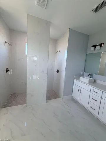 Bathroom with a marble finish shower, vanity, and light marble finish floors