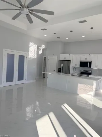 Unfurnished living room featuring light marble finish flooring, ceiling fan, french doors, recessed lighting, and a high ceiling