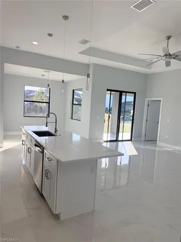 Kitchen featuring open floor plan, light stone countertops, a kitchen island with sink, light marble finish floors, and recessed lighting
