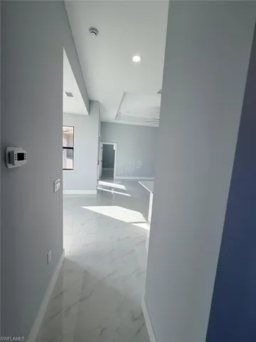 Hall with light marble finish flooring and recessed lighting