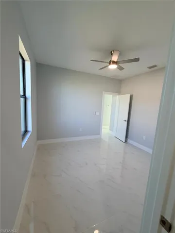Spare room featuring light marble finish flooring and ceiling fan