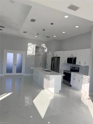 Kitchen featuring stainless steel appliances, pendant lighting, white cabinetry, recessed lighting, and a center island with sink