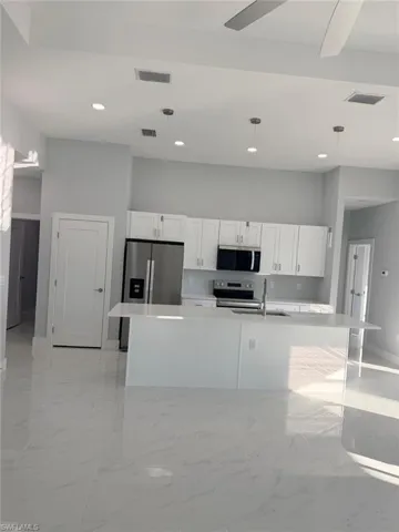 Kitchen featuring white cabinetry, decorative light fixtures, a kitchen island with sink, appliances with stainless steel finishes, and recessed lighting