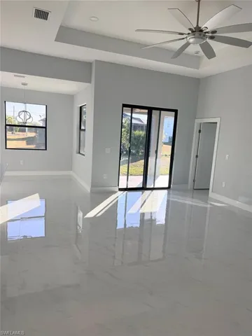 Spare room featuring light marble finish floors, a tray ceiling, healthy amount of natural light, and recessed lighting
