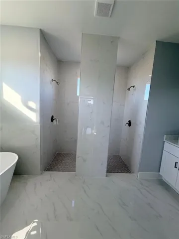 Full bath featuring a marble finish shower, light marble finish floors, a freestanding bath, and vanity