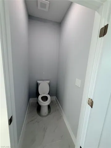 Bathroom with toilet and light marble finish floors