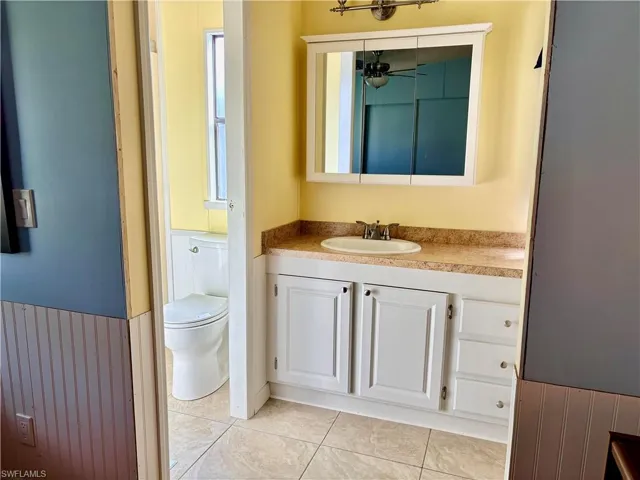 Bathroom with vanity, light tile patterned flooring, and a wainscoted wall
