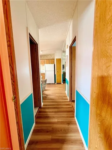 Corridor with a textured ceiling and wood finished floors
