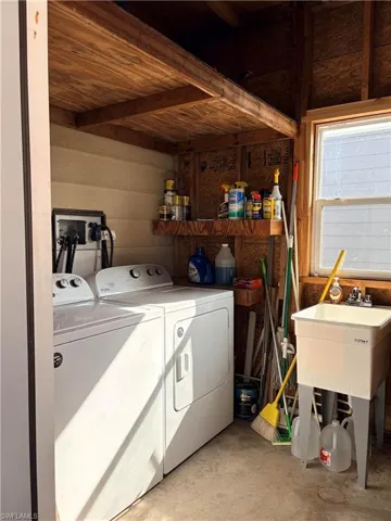 Laundry room featuring unfinished concrete flooring, washing machine and dryer, and wood walls