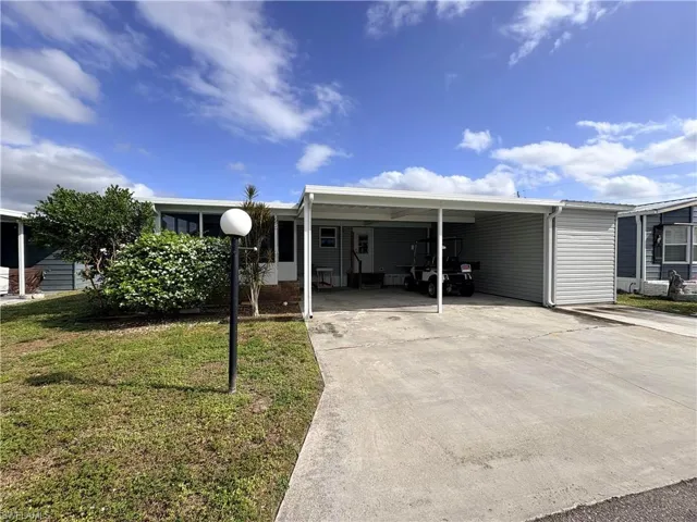 Manufactured / mobile home with a front yard, driveway, and a carport