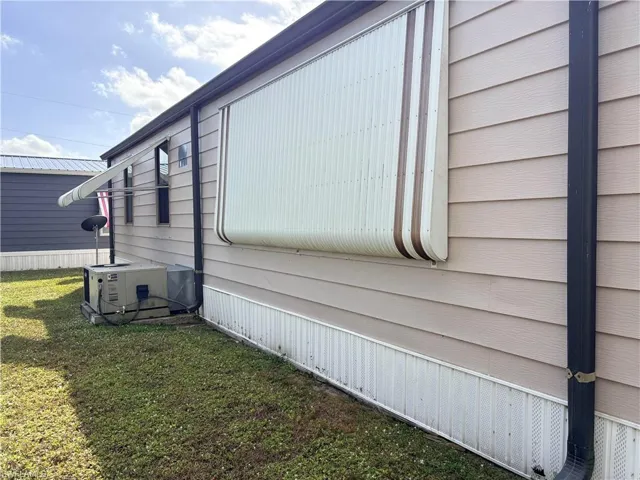 View of property exterior with a lawn and a central air condition unit