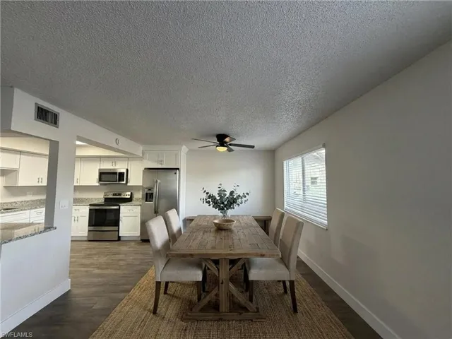 Dining area featuring dark wood-type flooring, a textured ceiling, and a ceiling fan