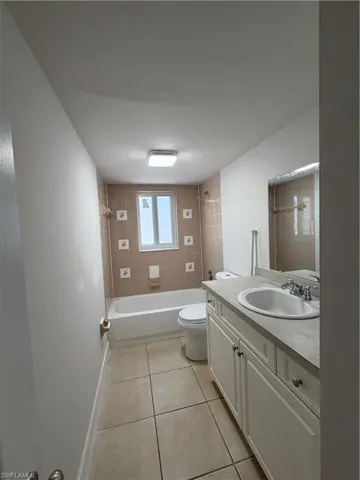 Bathroom featuring shower / bathtub combination, vanity, and light tile patterned floors