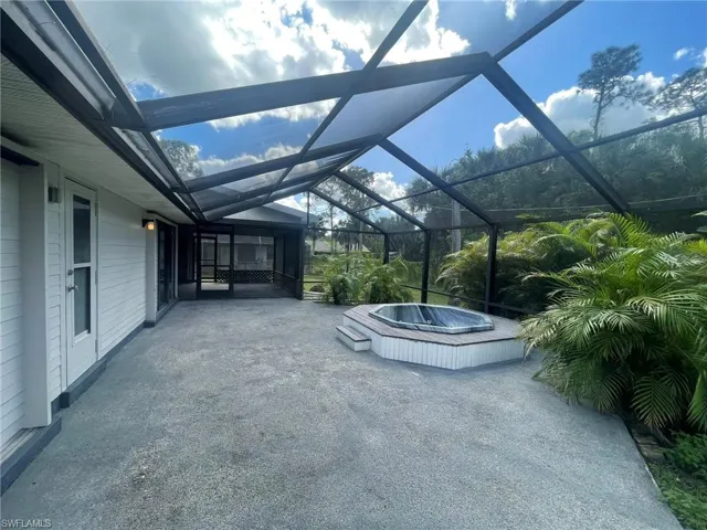 View of patio with a lanai and a hot tub